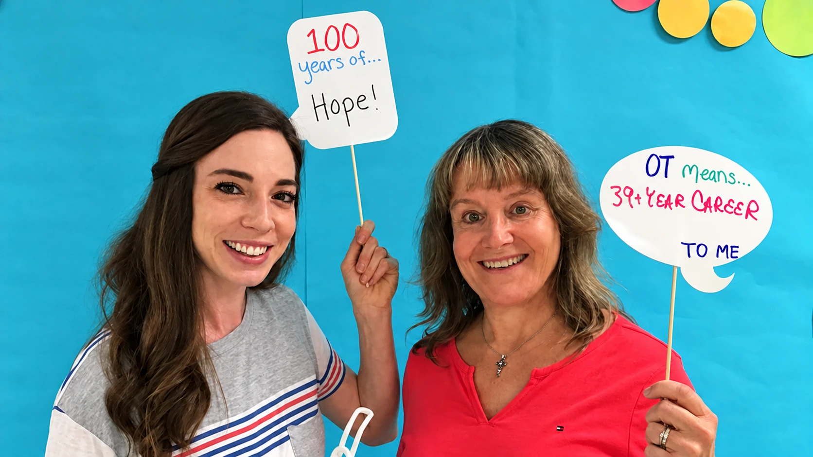 Two attendees holding occupational therapy signs at an ArizOTA gathering.