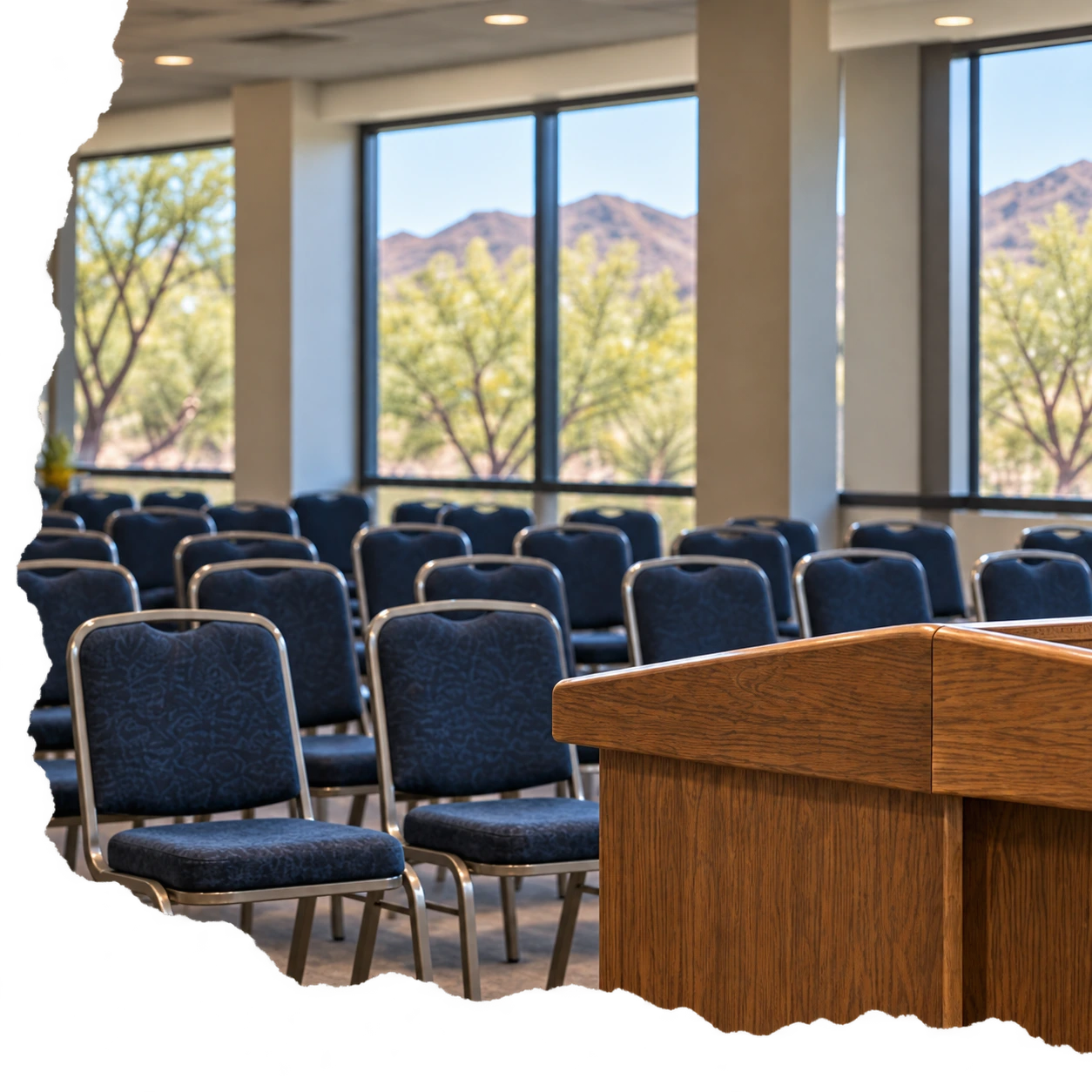 Blue conference chairs facing a wooden podium, with Arizona foothills visible through the windows.